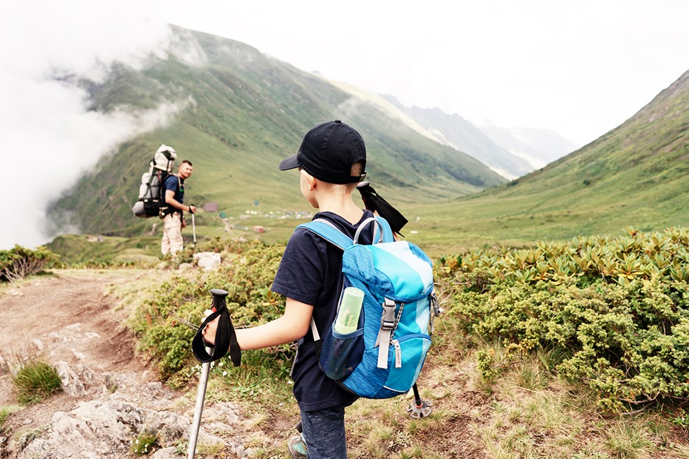 Dad and son hiking with backpacks.