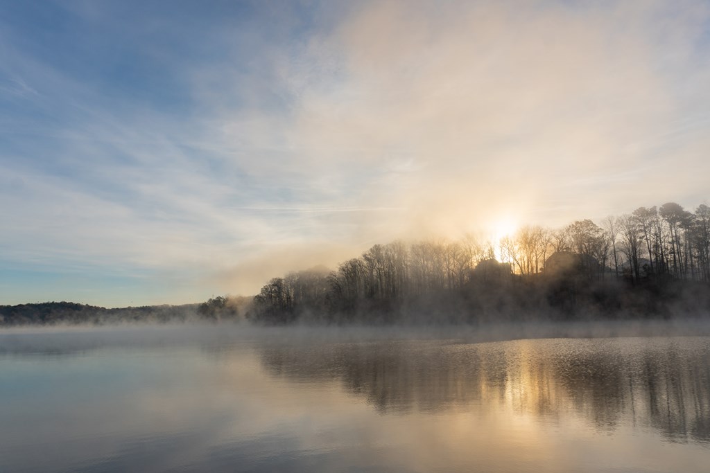 Fog rises on the water of Lake Lanier in Georgia at sunrise under a blue and orange sky; landscape