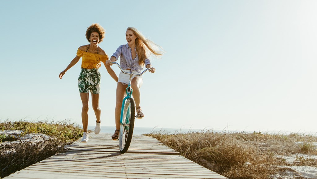 Two friends having fun on a beach boardwalk.