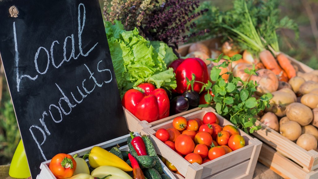 Counter with fresh vegetables and a sign of local products.