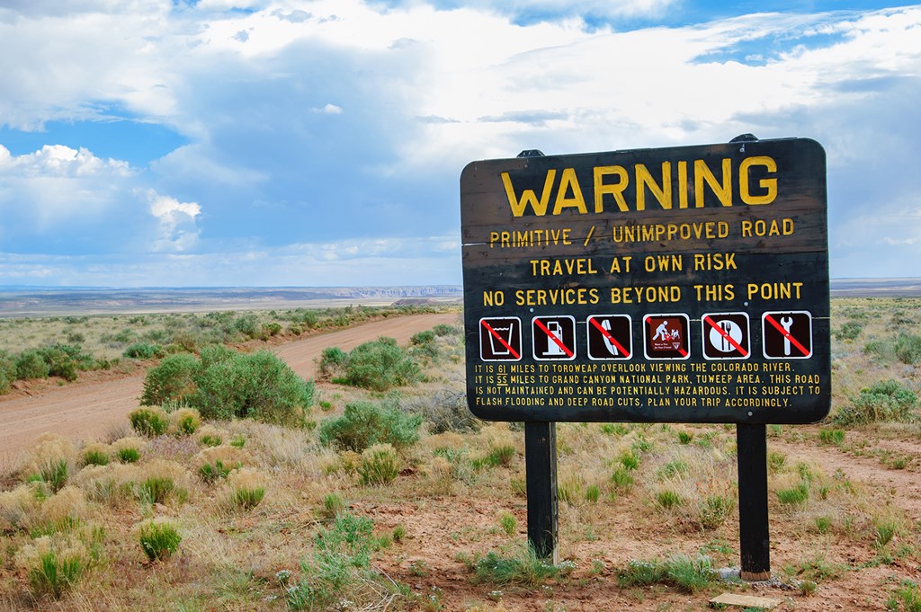 Warning sign declaring absence of services on the unpaved dirt road through the desert to Toroweap point in Grand Canyon national park, Utah, USA