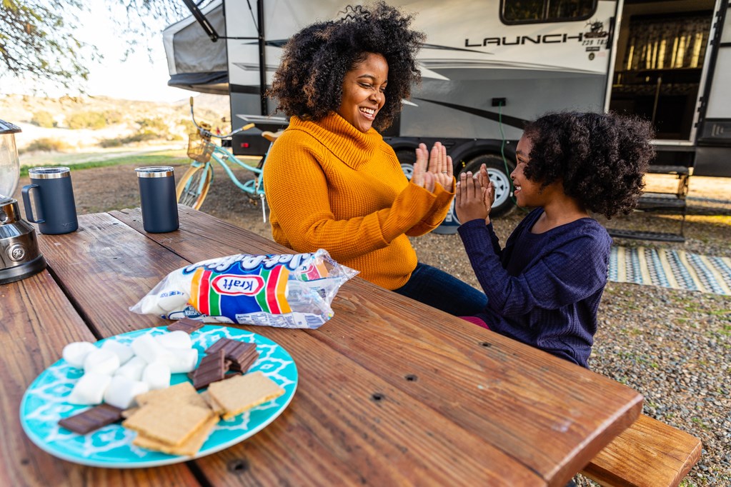 Mother with child playing patty cake at campsite