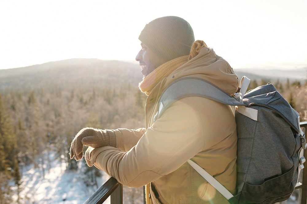 Happy young man looking at majestic landscape on sunny winter day