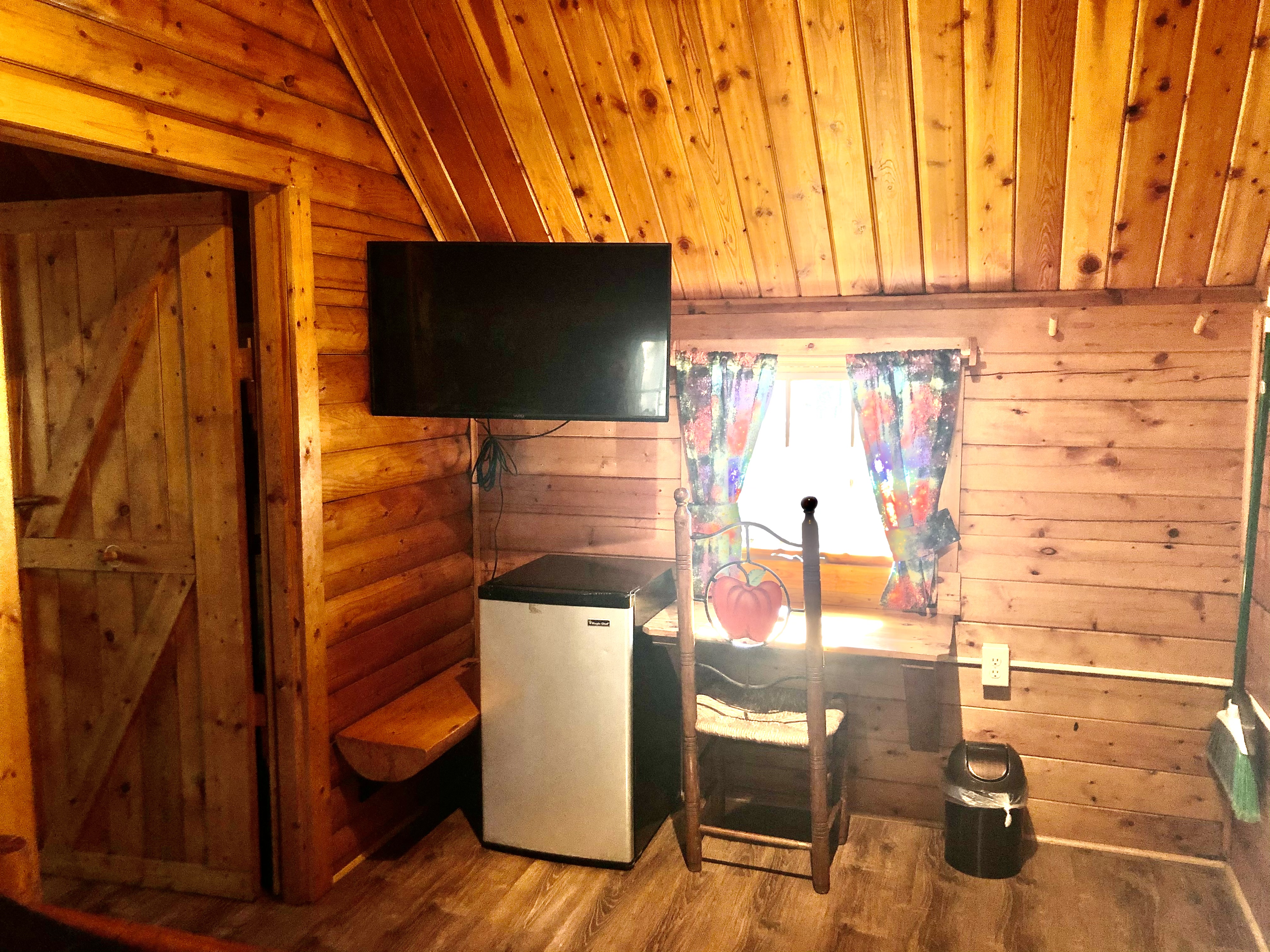 Two room cabin front room has a tv with cable connection and a mini-refrig.