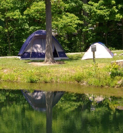 nice little camp site with a side perfect for you larger tent next to a small fishing pond