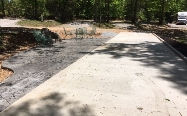 Patio Site with  concrete RV pad, concrete patio with stone fire pit, glider, table and 4 chairs and a Blackstone griddle.