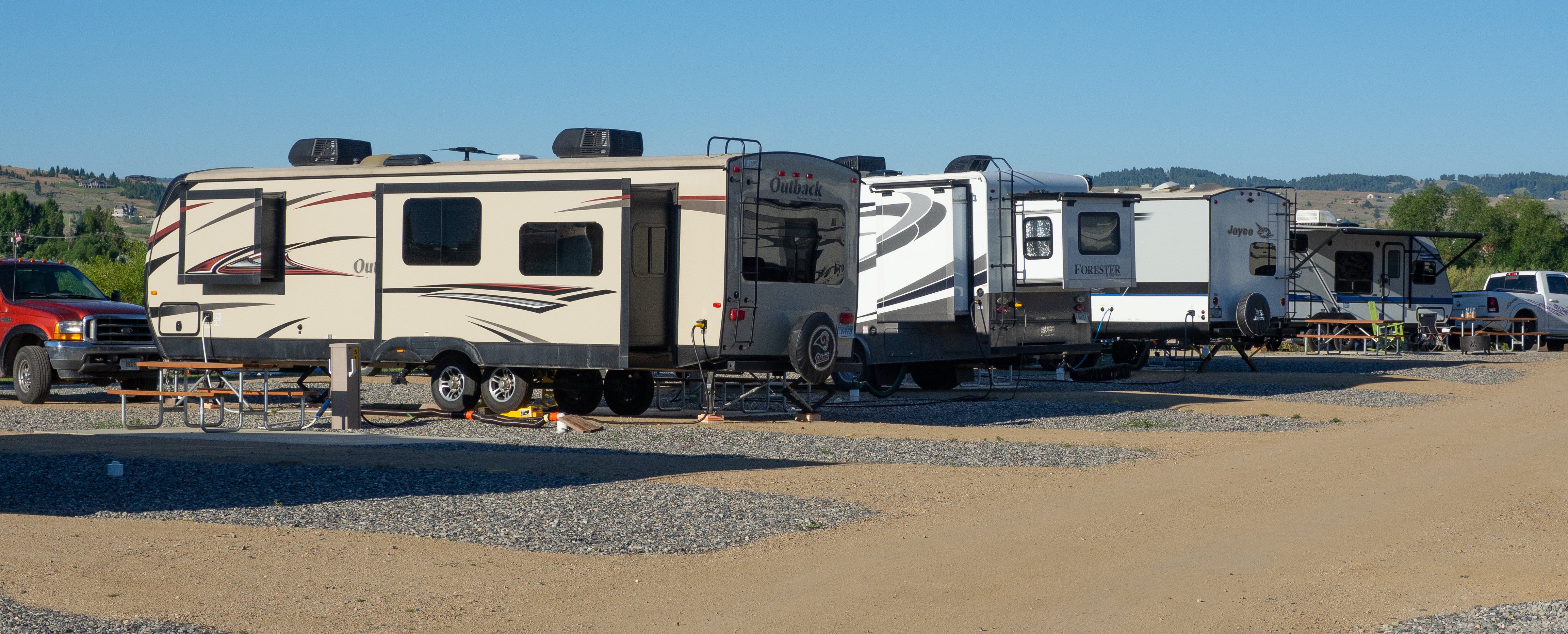 Premium 50amp Full Hookup, Pull-through Site with patio and colorful rocking chairs.