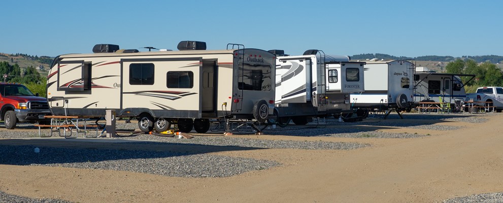 Premium 50amp Full Hookup, Pull-through Site with patio and colorful rocking chairs.