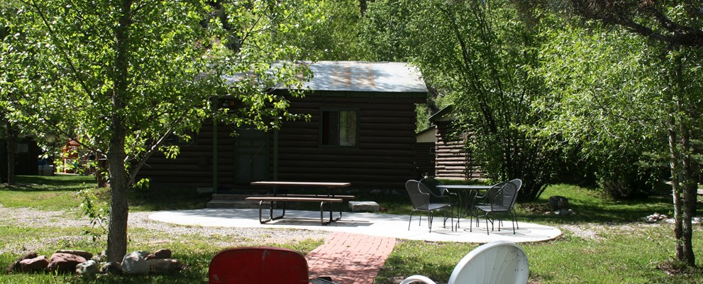Outdoor patio and firepit looking from the riverbank toward cabin 9