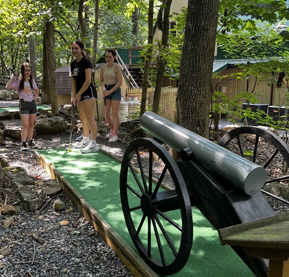 Girl practicing her mini-golf putt with friends at Gettysburg KOA