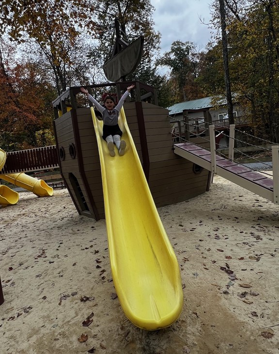 Girl sliding down yellow slide at Gettysburg KOA playground