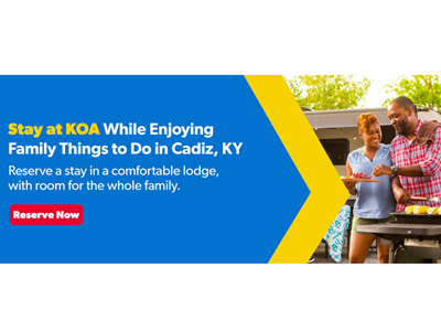 Couple smiling and serving food outside their RV Site at Kentucky Lakes / Prizer Point KOA