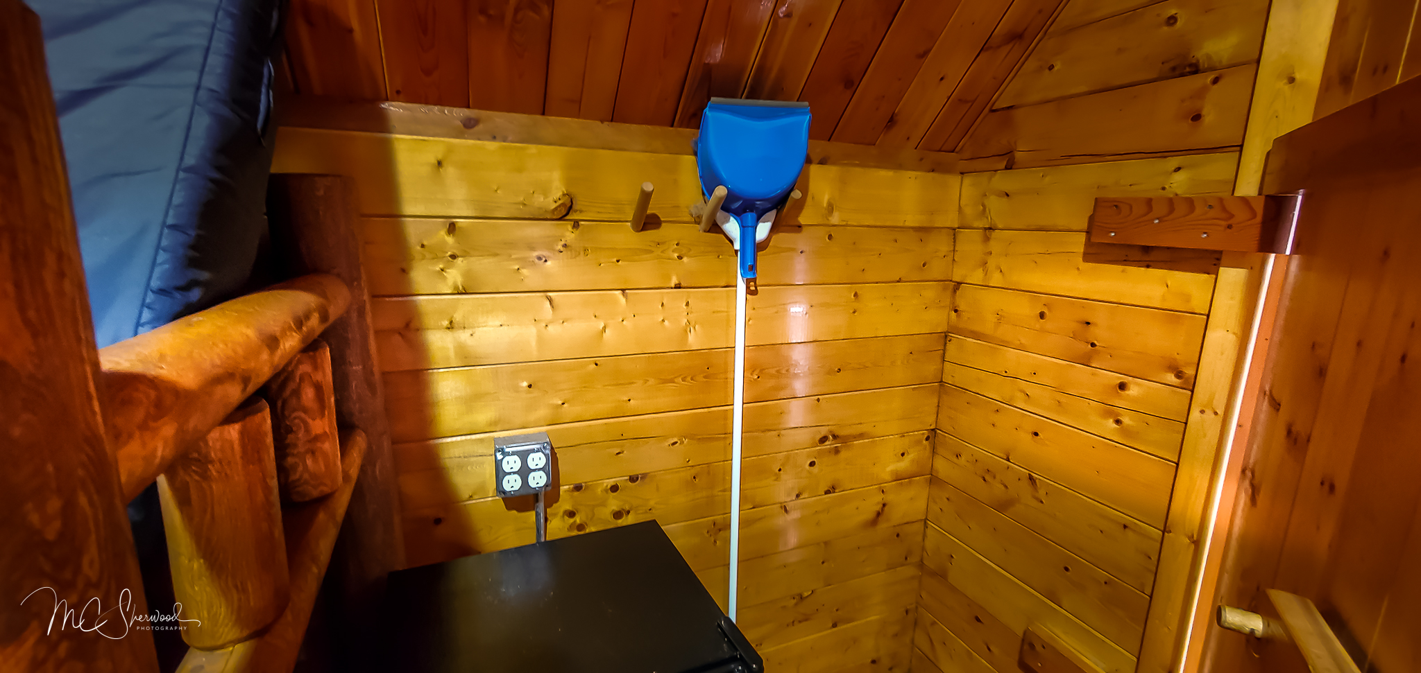 One-room rustic camping cabin interior - dorm fridge and broom