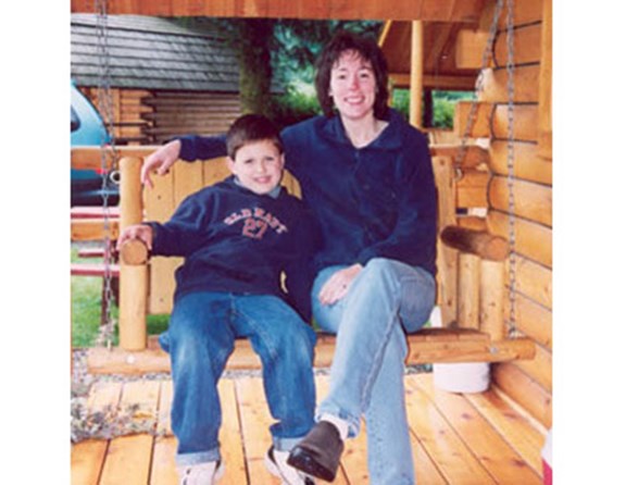 Mother & son laugh and swing on their Kamping Kabin porch.