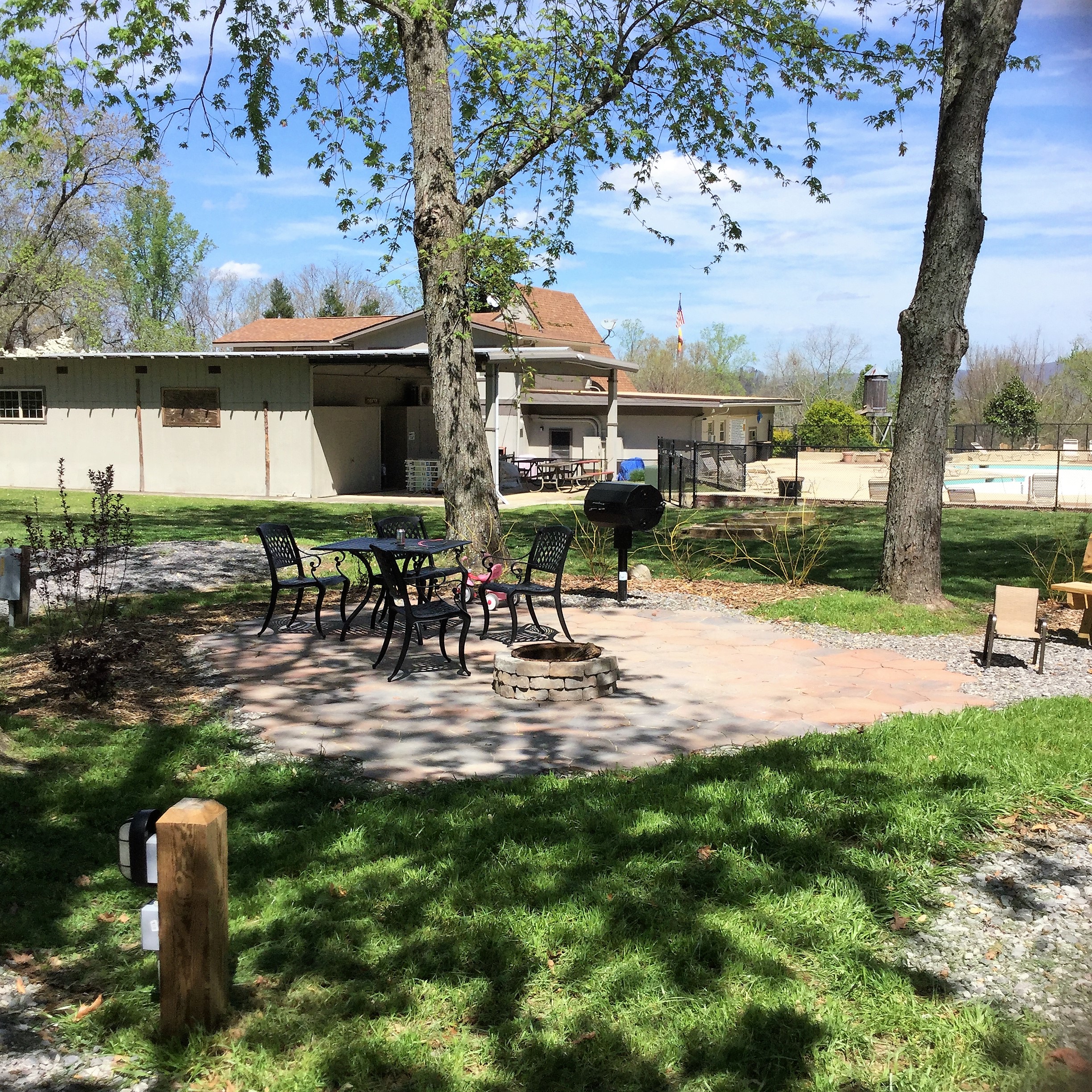 A site with extra amenities, patio, smoker grill, stacked fire ring, and shady.