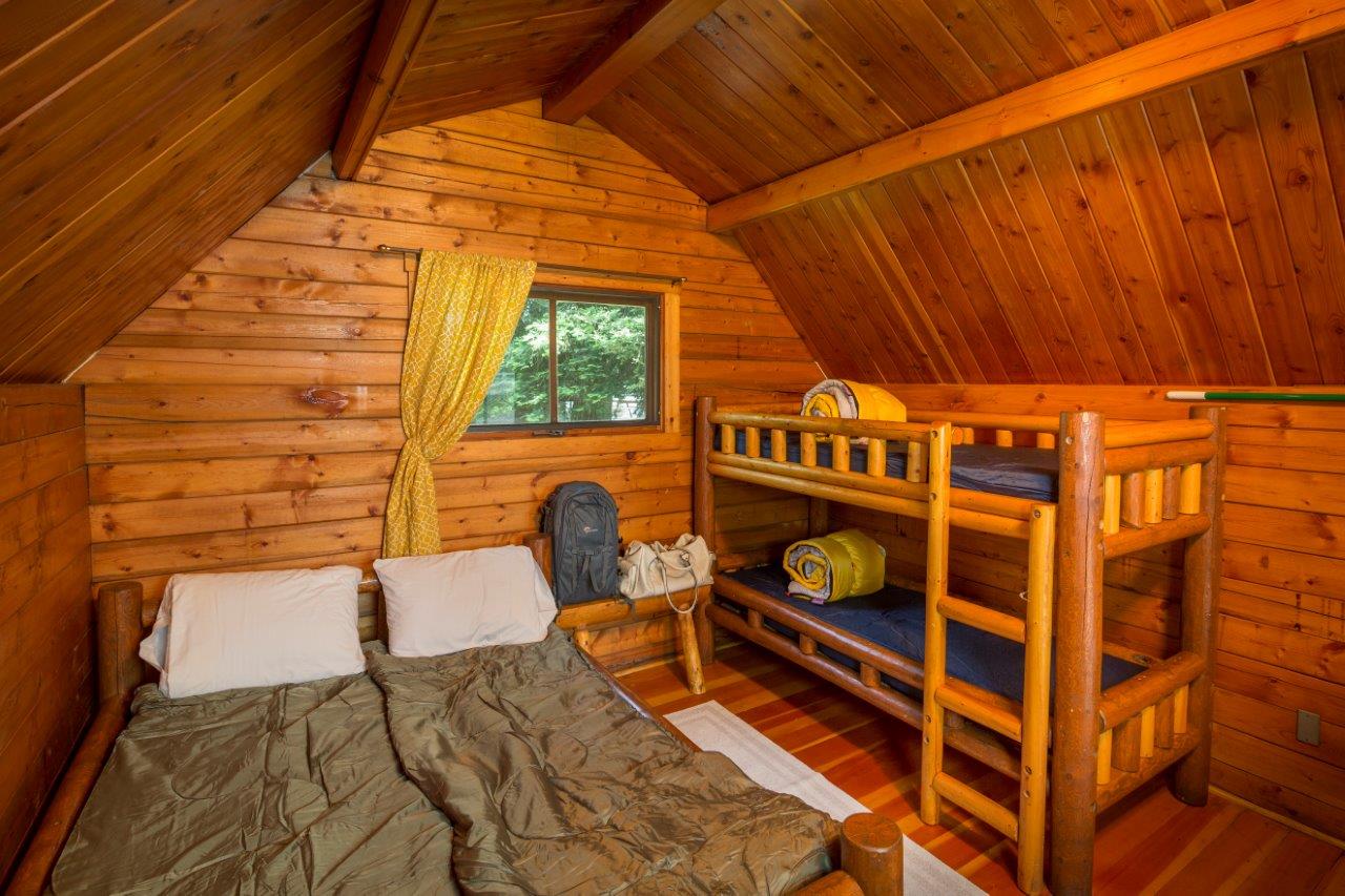 Inside of our camping cabins(linens/sleeping bags not included).  A full size bed and a set up twin bunk beds, TV with cable.  A fire ring, picnic table and parking for 1 vehicle at each cabin site.